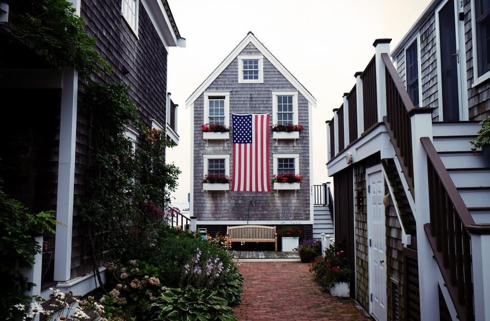 An American flag hanging from the front of a neighborhood home