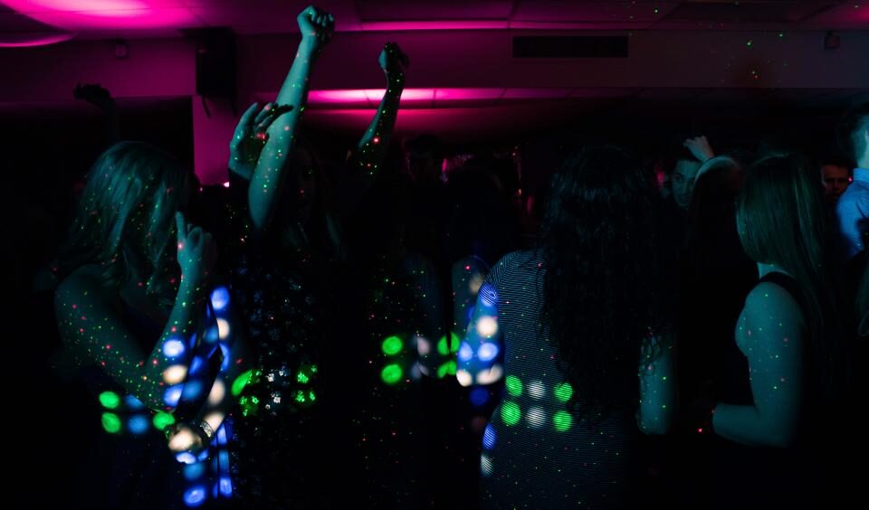 A packed dance floor under colored lights at a late-night venue